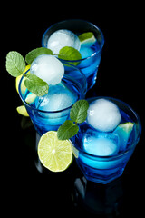 Delicious cocktails with ice balls, mint and lime on black background