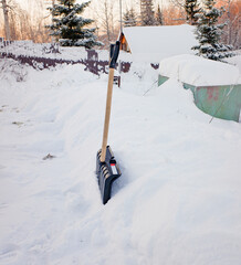 a black plastic shovel with a wooden handle stuck in fluffy white snow