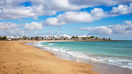 View of Playa de los Pocillos beach in Puerto del Carmen town, Lanzarote. Panorama of sandy beach with turquoise ocean water, white houses of tourist resort on Canary Islands, Spain