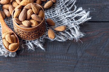 almonds in a wooden bowl and spoon close-up. almonds on a wooden background.