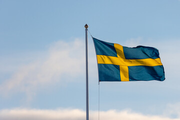 Swedish flag on a pole flying in the wind. Space for text
