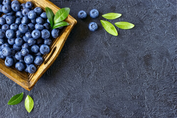 fresh blueberries on a wooden tray top view. background with fresh ripe blueberries and green leaves.