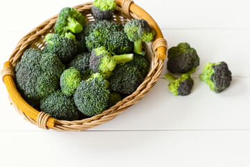 fresh broccoli in a wicker basket top view. white background with fresh broccoli.