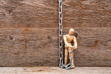 Wooden mannequin with a metal chain on wooden background