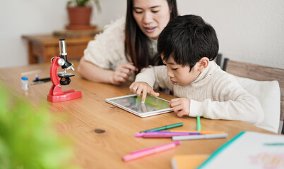 Asian boy using digital tablet indoor - Mother and child using technology to study at home