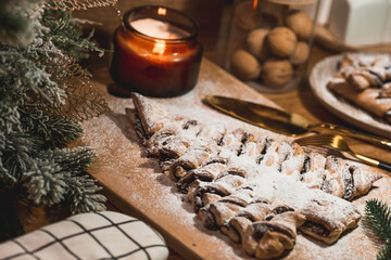 New Year's table. Treats for guests. Puff pastry cake with chocolate in the form of a Christmas tree on a wooden background. The concept of a family holiday. A copy of the space for the text.