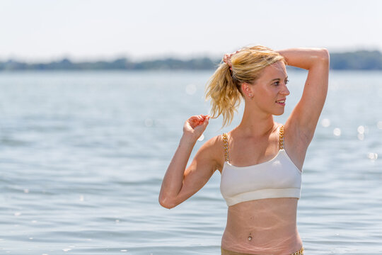 Young attractive blonde girl with perfect sport body in bikini on a beach in the summer