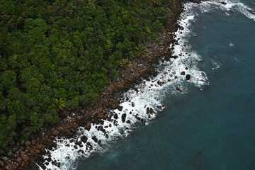 Sea and coastline of the island with rocks and forest, top view, white sea foam