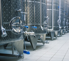 Stainless steel tanks for fermenting grapes. Winery interior, selective focus
