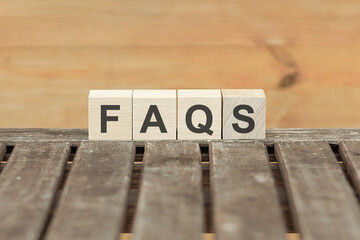 Faqs concept with wooden block on wooden table background