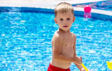 Happy child in the pool playing with a water gun.