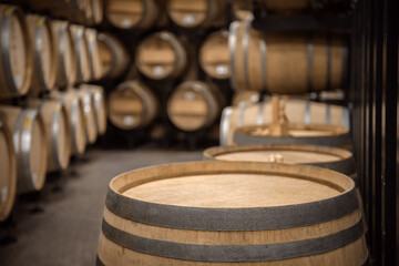 Top of oak wine barrel in front of soft focused wine cellar interior