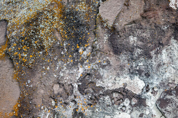 Natural stone background with rough textured surface and lichen. Spots of orange and white lichens...