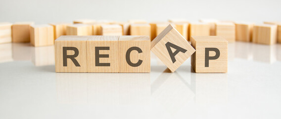 recap text on a wooden blocks, gray background.