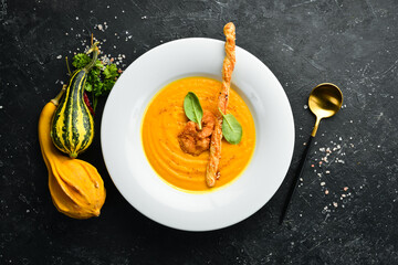Pumpkin soup with pumpkin seeds. Autumn menu. In a white plate. Top view.