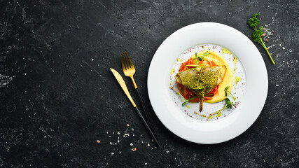 Roasted sea bass fillet with vegetables on a white plate. Top view. Rustic style.