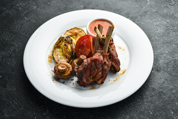 Baked lamb ribs with vegetables on a plate. Top view.