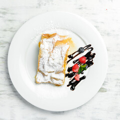 Dessert. Apple strudel with berries and chocolate on a plate. Top view.