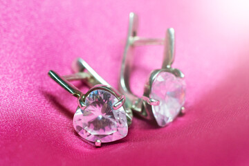 Silver diamond earring on pink fabric
