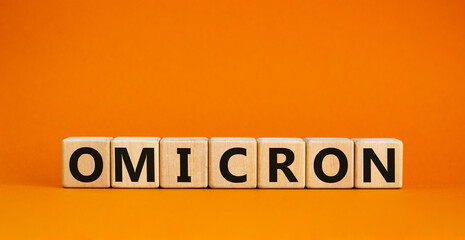 Covid-19 new omicron strain symbol. The concept word Omicron on wooden cubes. Beautiful orange background. Copy space. Medical and COVID-19 new omicron strain variant virus concept.