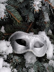 masquerade mask on fir branches in the snow with selective focus
