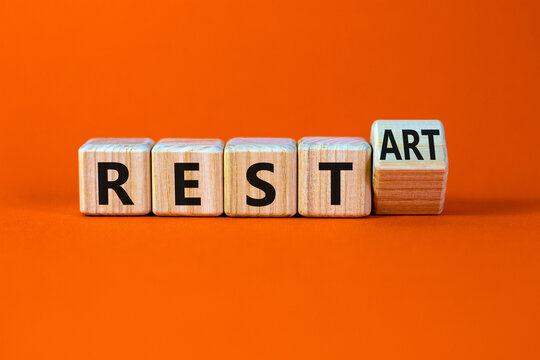 Rest and restart symbol. Turned a wooden cube and changed the word rest to restart. Beautiful orange table, orange background, copy space. Business, rest and restart concept.