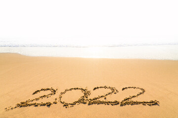 2022 happy New Year coming concept. Brightness Sunlight and White waves are lapping towards the sand beach.