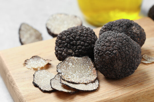 Black truffles with wooden board on table, closeup