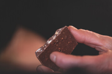 piece of chocolate with almond chips in human hand