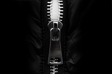White lock with a zipper on clothes, jacket, jacket close-up on a black background. Lightning. © Gudman