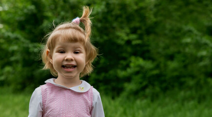 Happy smiling little girl in a meadow in the park. Facial expression, kid and emotion