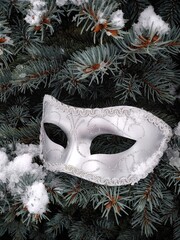 masquerade mask on fir branches in the snow with selective focus
