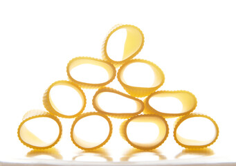 Close-up, studio shot with soft shadow of a whole wheat Italian pasta- tortiglioni- neatly arranged in the shape of a pyramid. Food background