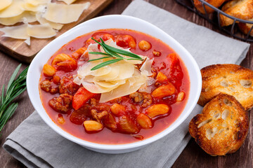 Minestrone soup served with crispy bread, on wooden background, horizontal, closeup