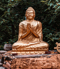 Złoty posąg Buddy na roślinnym tle. - obrazy, fototapety, plakaty