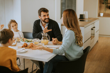 Young happy family talking while having breakfast at dining table