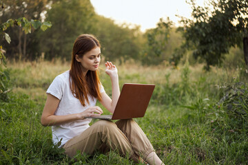 woman outdoors sitting on the grass with laptop summer vacation communication