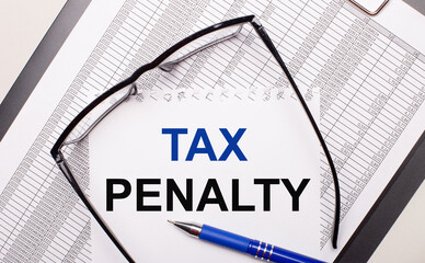 On a light background, a report, black-framed glasses, a pen and a sheet of paper with the text TAX...