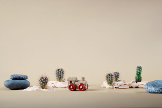 background image of wooden toy steam locomotive in desert with stones and cactuses on beige backdrop