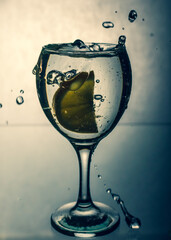 Lemon slice splashes in a water glass