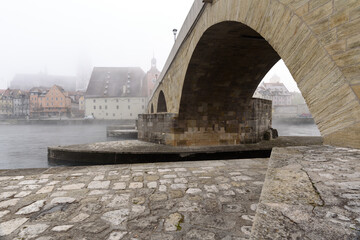 Steinerne Br&uuml;cke Regensburg im Nebel im Winter 