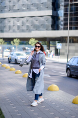 a fashionable girl in trousers, a raincoat, a blouse with a handbag walks around the city. Business...