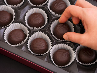A woman hand taking chocolate candy from a box.