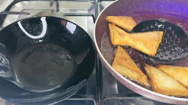 Done fried stuffed Sambusek ready to be removed from the frying pan to the plate
