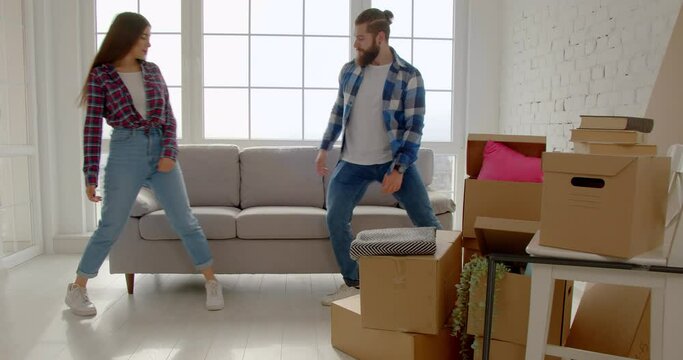 New home concept, a young couple moving to a new apartment. Happy family moving a new couch into the living room and falling on it to rest. slow motion