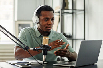 Portrait of African-American man speaking to camera while recording podcast at home