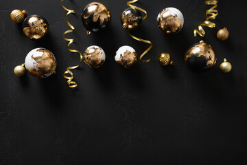 Gold and black baubles on a black background with Christmas decorations. View from above. Space for text.
