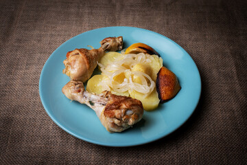 Lemon chicken thighs, garnished with potatoes and onion, cooked in the oven.