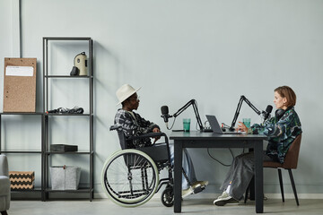Full length portrait of person in wheelchair giving interview while recording podcast in studio, copy space