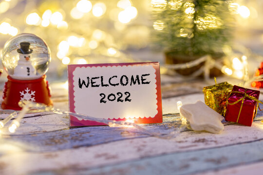 welcome 2022 writing on greeting card with christmas decoration and lights background